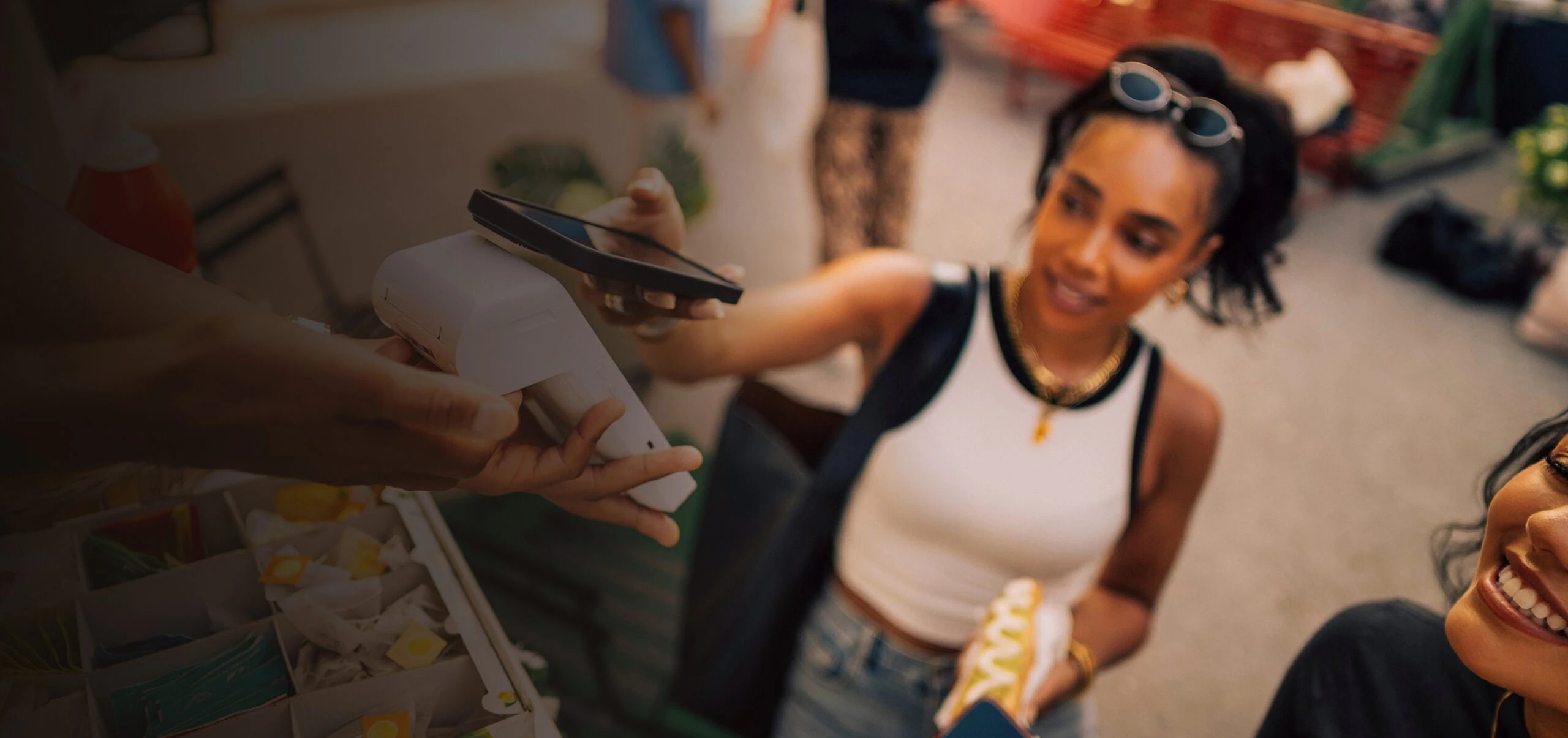 A young woman purchasing a hotdog by paying with her phone