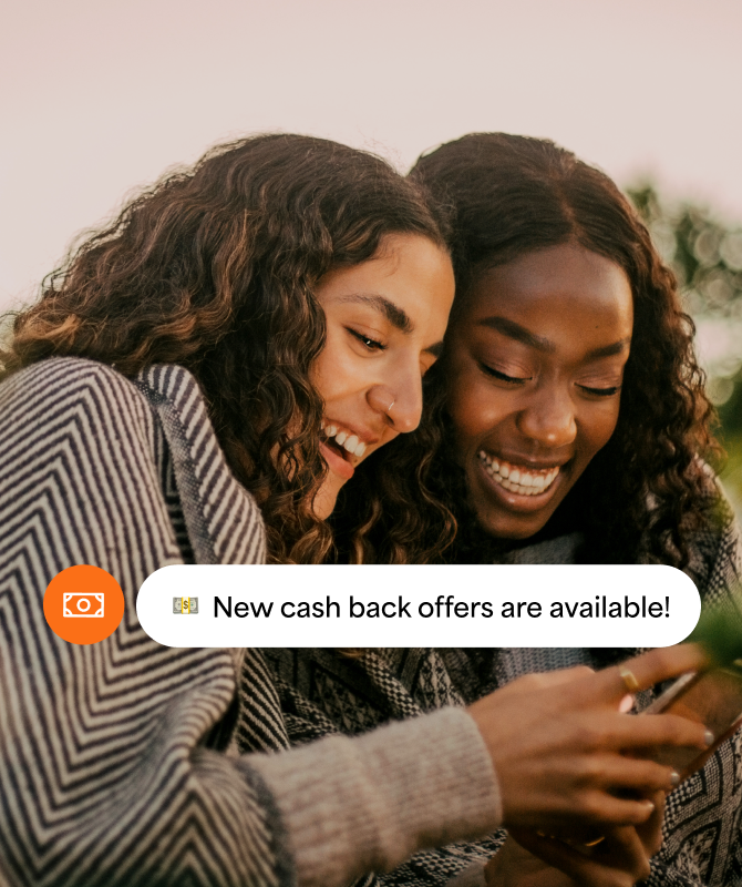 Two women looking at their phone with a cash back offers notification.